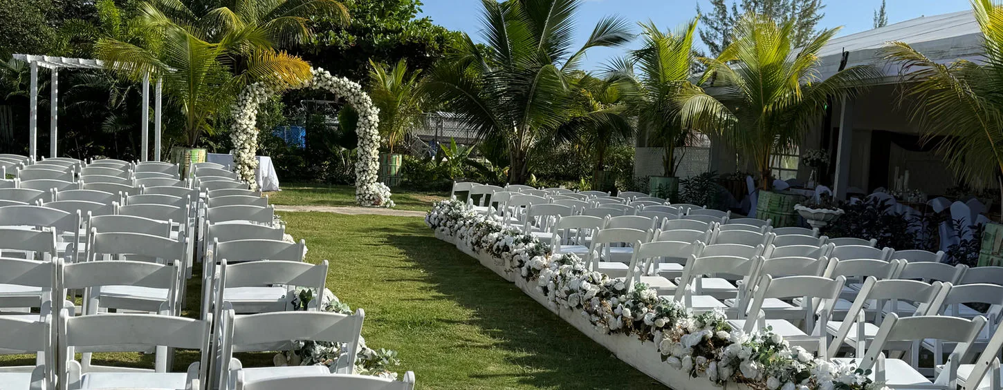 White wedding chairs and a flower-lined aisle in Savvy’s garden